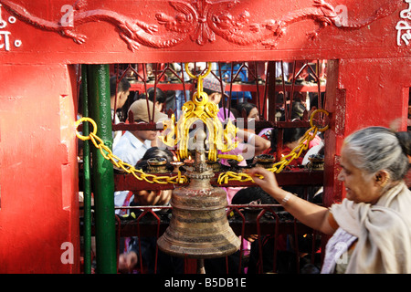 Alte hinduistische Dame läuten außerhalb der gepackten Bhadrakali Tempel in Kathmandu-Nepal Stockfoto