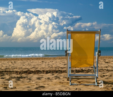 Einzigen Liegestuhl auf dem sandigen Strand, Meer mit Pferden, dramatischer Himmel Anfang September, Bibione, nördliche Italien, Adria, Eur Stockfoto