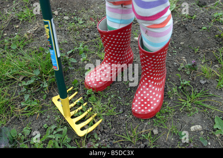 Junge Mädchen tragen rote Gummistiefel Stiefel auf einer Zuteilung Stockfoto