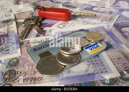 Autoschlüssel Kreditkarte und Münzen auf einem Hintergrund von zwanzig Pfund-Noten Stockfoto