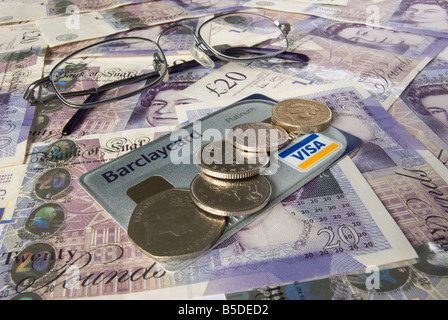Gläser-Kreditkarte und Münzen auf einem Hintergrund von zwanzig Pfund-Noten Stockfoto