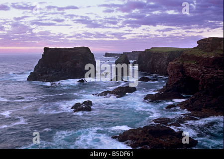 Sonnenuntergang am Eshaness Basaltfelsen, Moo Stapel auf der linken und tief erodierten Küste mit Höhlen, Northmavine, Shetland-Inseln, Schottland Stockfoto