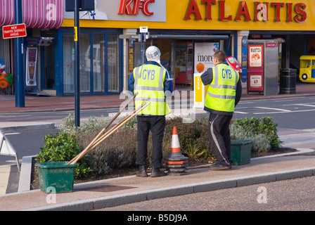 Zwei Arbeiter mit fluoreszierenden Westen für Sicherheits- und Gesundheitsvorschriften, die Arbeiten auf den Straßen Stockfoto