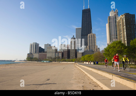 Jogger und Radfahrer am Lake Michigan Ufer mit der in der Nähe von North Skyline hinter Oak Street Beach, Chicago, Illinois, USA Stockfoto