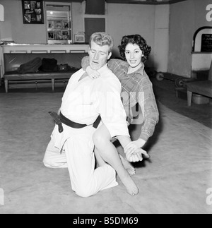 Frauen Verteidigung: Judo Experte Joe Robinson zeigt Valerie Dave einige Selbstverteidigung bewegt sich auf einen willigen Freiwilligen. Februar 1957 Stockfoto