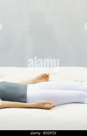 Frau liegt auf dem Rücken auf Futon, Handflächen nach oben gerichtet, beschnitten Ansicht Stockfoto
