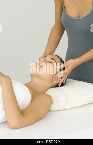 Frau auf Rücken liegend empfangen Gesichtsmassage Stockfoto