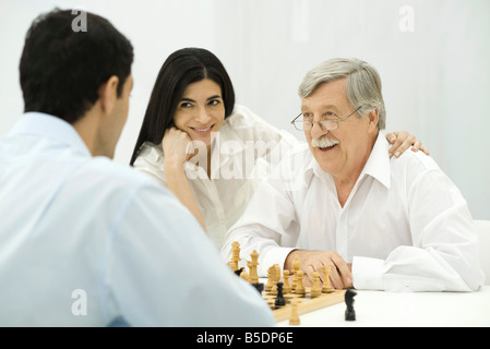 Leute spielen Schach, Frau sitzt mit der Hand auf die Schulter des Mannes senior Stockfoto