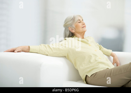 Entspannen Sie sich auf die Couch und geschlossenen Augen Senior Frau Stockfoto