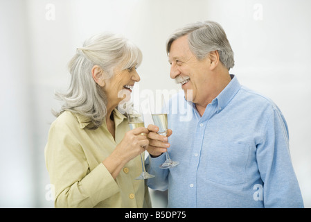 Älteres Paar halten Sektgläser, Lächeln einander an Stockfoto