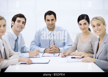 Geschäftsmann, sitzen mit Kollegen am Konferenztisch, lächelnd in die Kamera Stockfoto