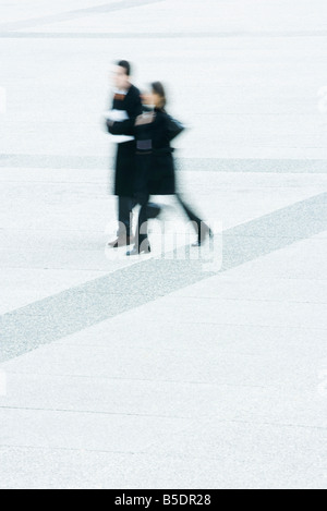 Unternehmer und Unternehmerin, die zusammen über öffentliche Platz spazieren Stockfoto