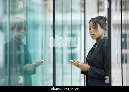 Geschäftsfrau mit Handy, Blick in die Kamera Stockfoto