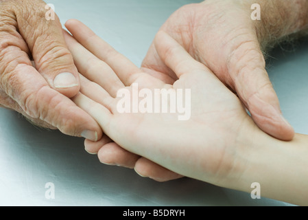 Mann, der jungen Menschen Hand, Handfläche nach oben, hält beschnitten Ansicht Stockfoto