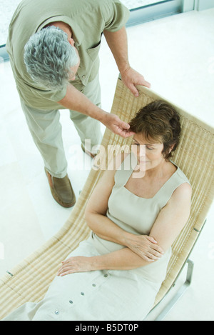 Entspannend auf Liegestuhl, Frau Mann beugte, um ihr Haar zu berühren Stockfoto