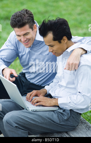 Geschäftspartner mit Laptop zusammen im Freien, eines Mannes, der Arm auf der anderen Schulter Stockfoto