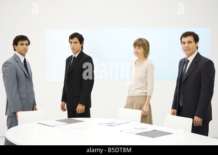 Geschäftspartnern herumstehen Konferenztisch, Blick in die Kamera Stockfoto