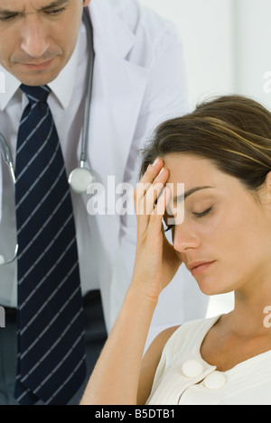 Frau mit Kopf, Arzt lehnt sich hinter ihr Stockfoto