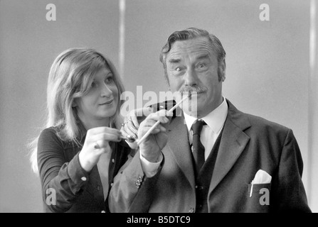 Pfeife rauchen-Champion Robert Locke von Hayes, Middlesex, verfolgt Schreibkraft Liliana Perez, wie der TV-Werbung während der britischen nationalen Pfeife rauchen Meisterschaft. ; Mai 1975 Stockfoto