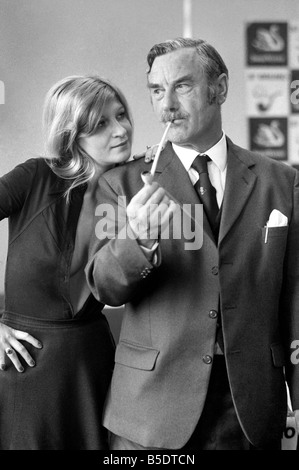 Pfeife rauchen-Champion Robert Locke von Hayes, Middlesex, verfolgt Schreibkraft Liliana Perez, wie der TV-Werbung während der britischen nationalen Pfeife rauchen Meisterschaft. ; Mai 1975 Stockfoto