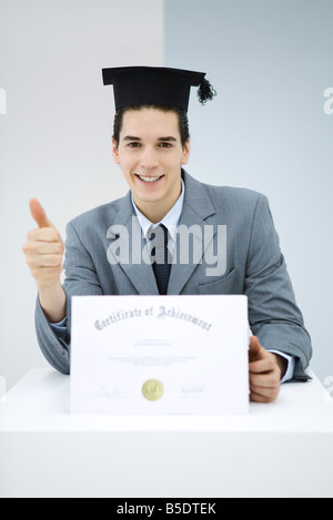 Junger Mann mit Diplom, mit dem Studium Mütze, Daumen-hoch-Geste Stockfoto