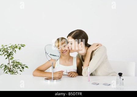 Junge Frau und preteen Schwester sitzen vor Spiegel, ältere Schwester, die jüngere Schwester Wange küssen Stockfoto