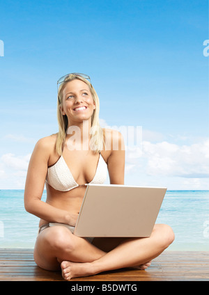 Junge Frau mit Laptop in der Nähe von Strand Stockfoto