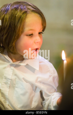 Junge Ausblasen der Kerze zur Taufe. Stockfoto