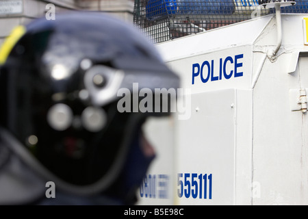 PSNI Police Service of Northern Ireland Riot Squad Offizier trug Schutzhelm und Visier vor gepanzerten landrover Stockfoto