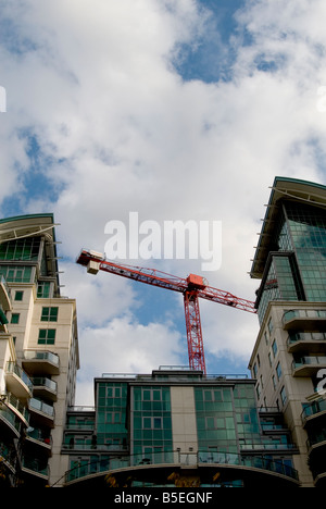 Ein Bild nach oben auf einem modernen Block aus London Wohnungen mit blauem Himmel ein Wolken. Ein große rote Kran ragt hinter. Stockfoto