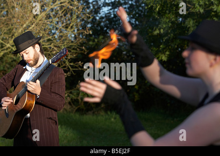 Mann, die Gitarre mit Firepoise Frau Feuer Tänzerin Spiel mit dem Feuer spielen Stockfoto