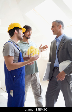 Zwei Männer im Gespräch mit Architekten auf Baustelle Stockfoto