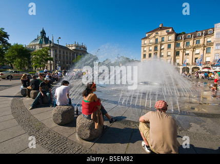 Menschen genießen die warme Sommersonne am Karlsplatz Brunnen München Bayern Deutschland Stockfoto