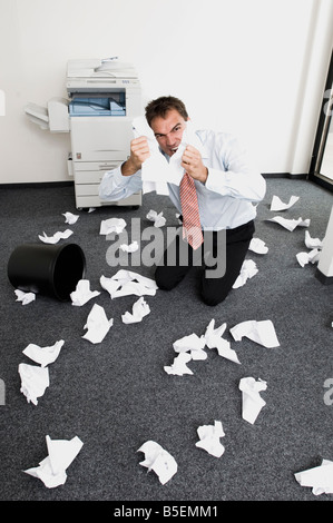 Geschäftsmann in Verzweiflung, kniend reißen Blatt Papier Stockfoto