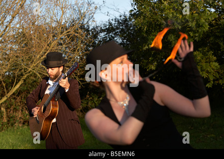 Mann, die Gitarre mit Firepoise Frau Feuer Tänzerin Spiel mit dem Feuer spielen Stockfoto