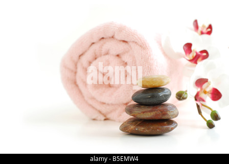 Rosa aufgerollt Handtuch mit einem Stapel von Steinen Massage und Orchidee auf weißem Hintergrund Stockfoto