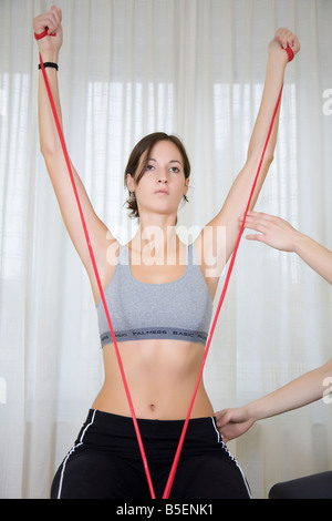 junge Frau, die Übungen mit Theraband auf Gymnastikball sitzend Stockfoto