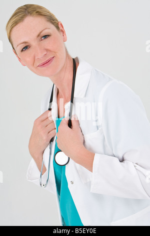 Eine Ärztin gekleidet in Scrubs und einem weißen Mantel, die wir gerne auf Kamera Stockfoto