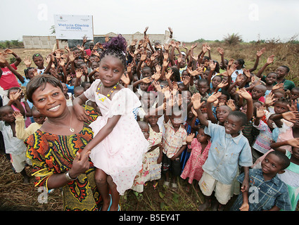 Die Mutter von Victoria Climbie präsentiert stolz eine Schule im Namen ihrer Tochter Bertha Climbie ist hier abgebildet, hält Victoria s Schwester Joelle und ist umgeben von zukünftigen Schüler der Schule die ich in Abobo die Côte d ' Ivoire im September 2008 eröffnet wird gebaut Stockfoto