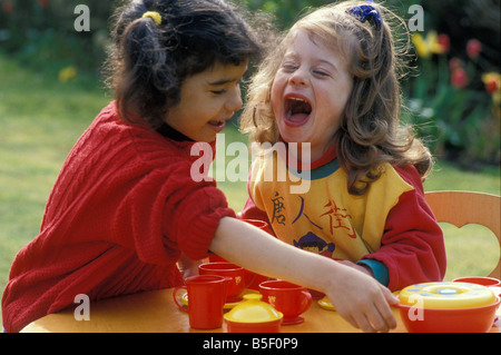 zwei Mädchen spielen mit Tee-Set im Garten Stockfoto