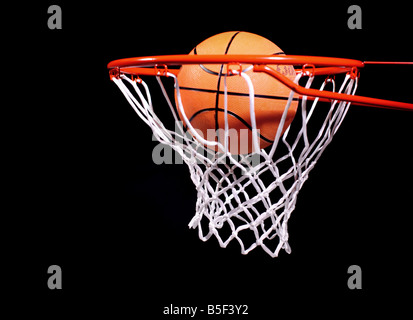 Basketball in Reifen auf schwarzen Hintergrund Stockfoto