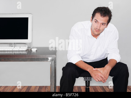 Reflektierende Geschäftsmann sitzt neben einem computer Stockfoto