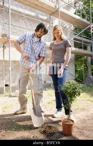 Junges Paar auf Baustelle, die Pflanzung eines Baumes Stockfoto