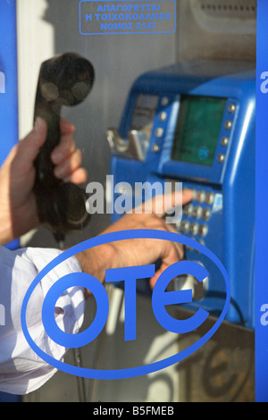 Mann Wählen einer Telefonnummer an einer öffentlichen Telefonzelle in Rhodos, Griechenland Stockfoto