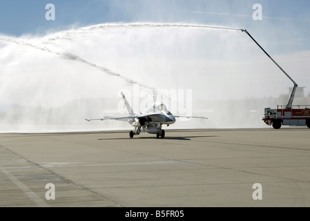 Eine f-18 Flugzeuge Taxis unter das Spray von Feuerwehrautos. Stockfoto