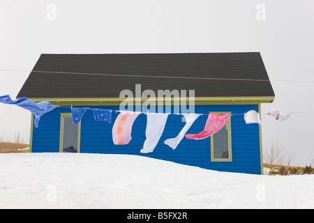 Trocknende Wäsche auf Clothline vor einem Haus auf Schnee, Iles De La Madeleine, Quebec, Kanada Stockfoto