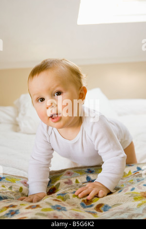 Porträt eines 10 Monate alten kaukasischen Babys krabbeln auf einem Bett Stockfoto