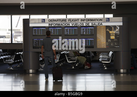 Mann sucht bei der Abreise Flug Informationstafel am Flughafen in Houston, Texas, USA Stockfoto