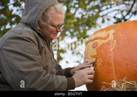 Eine Frau aus Nalls Bauernhofmarkt schnitzt einen Kürbis 2008 Shenandoah Valley Heißluftballon und Weinfest in Virginia. Stockfoto