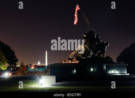 Iwo Jima Memorial in der Nacht mit dem Washington Monument und das Capitol Building Leuchten im Hintergrund. Stockfoto